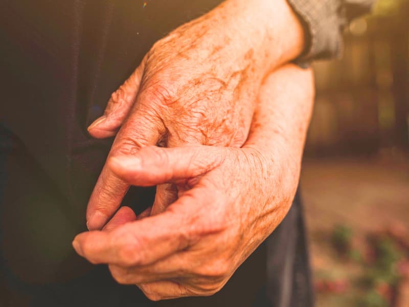 Photo of an old couple holding each other's hands used in a single premium term life insurance article of 2025.