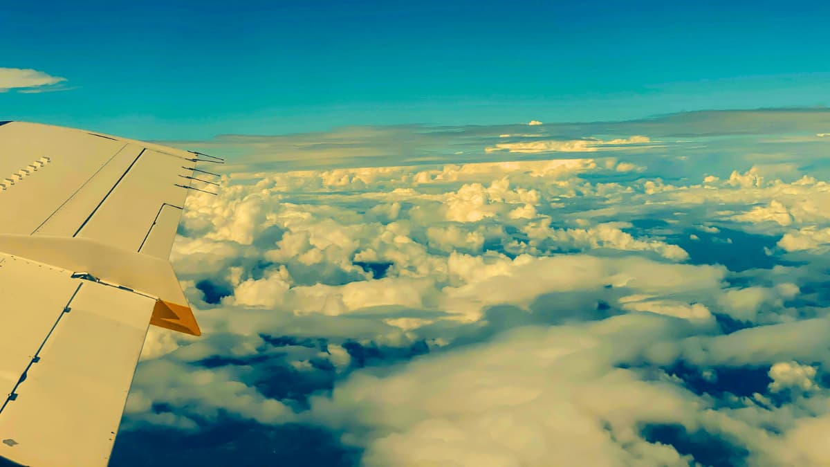 View from airplane wing flying above the clouds over Europe, symbolizing the start of a trip requiring valid Schengen Visa travel insurance to ensure medical protection during emergencies abroad.
