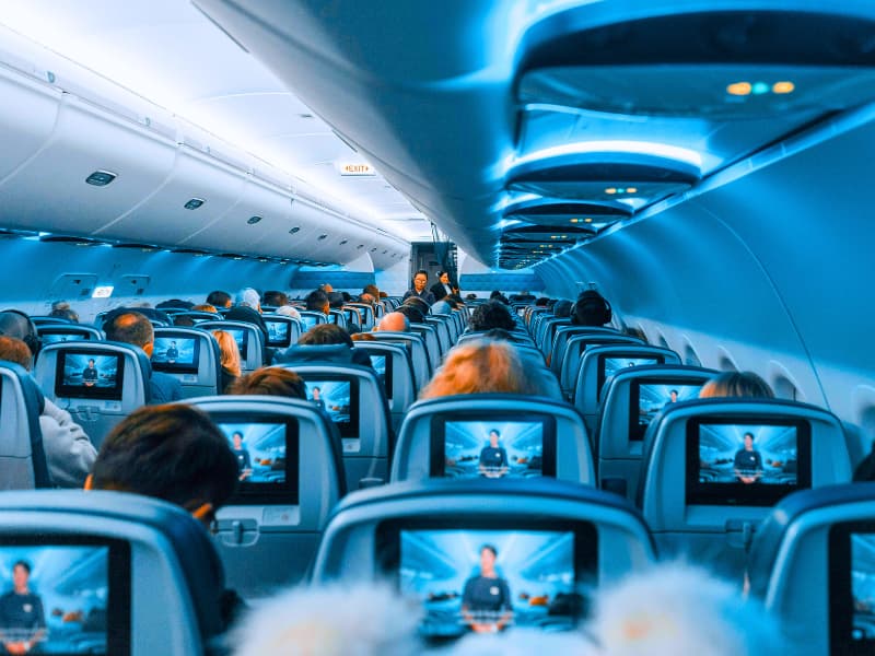 Passengers seated inside a European flight, emphasizing the importance of having Schengen Visa-compliant travel insurance for medical emergencies, flight delays, or unexpected accidents during the trip.