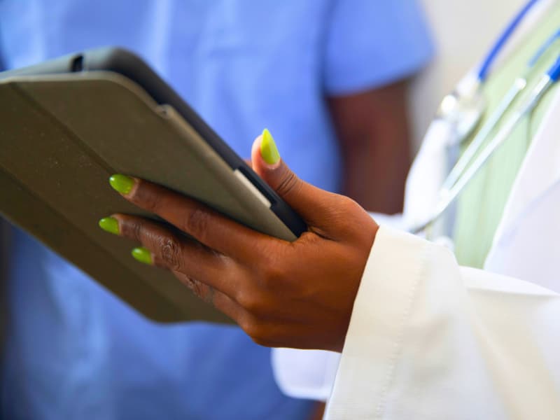 A doctor holding a digital tablet while reviewing records—highlighting the role of Health Insurance Deductibles in shaping access to efficient, tech-driven healthcare decisions.