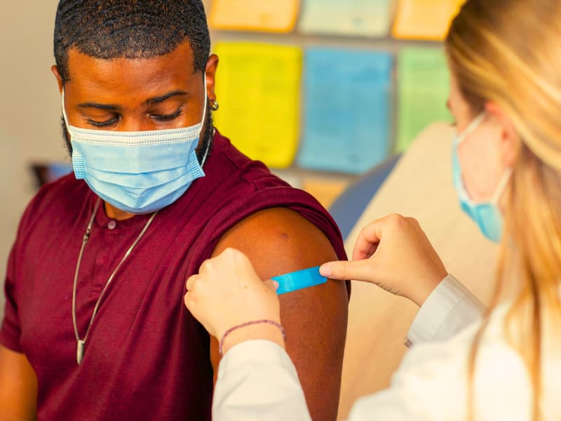 A nurse applies a bandage after giving a vaccine, representing the kind of preventive service often influenced by Health Insurance Deductibles and coverage policies.