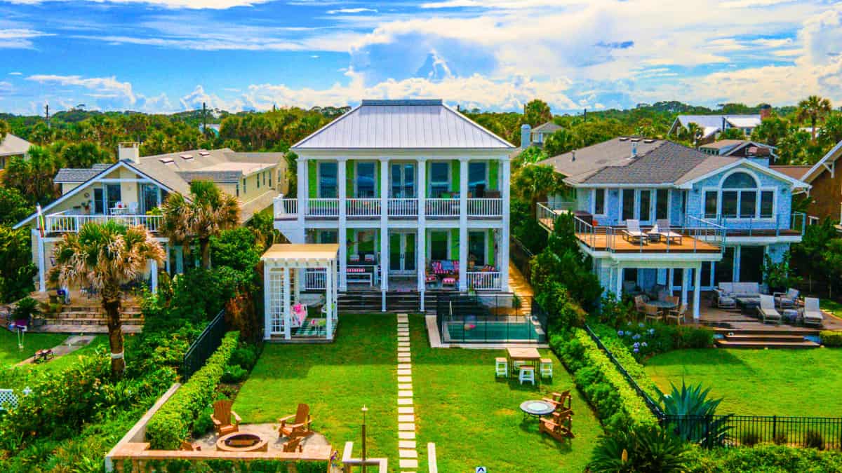 Beachfront home with lush green lawn, multiple patios, and coastal-style architecture – representing how property features influence homeowners insurance discounts in 2025.