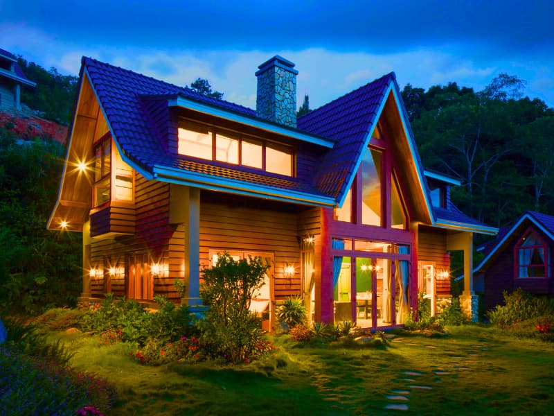 Cozy mountain chalet with night lighting, illustrating how elevation and seasonal risks influence a Homeowners Insurance Quote.