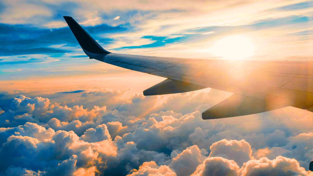 Airplane wing above the clouds during a stunning sunset—reminding travelers that while international adventures can be breathtaking, unexpected emergencies can happen anytime, making solid travel insurance for international travel an absolute must.