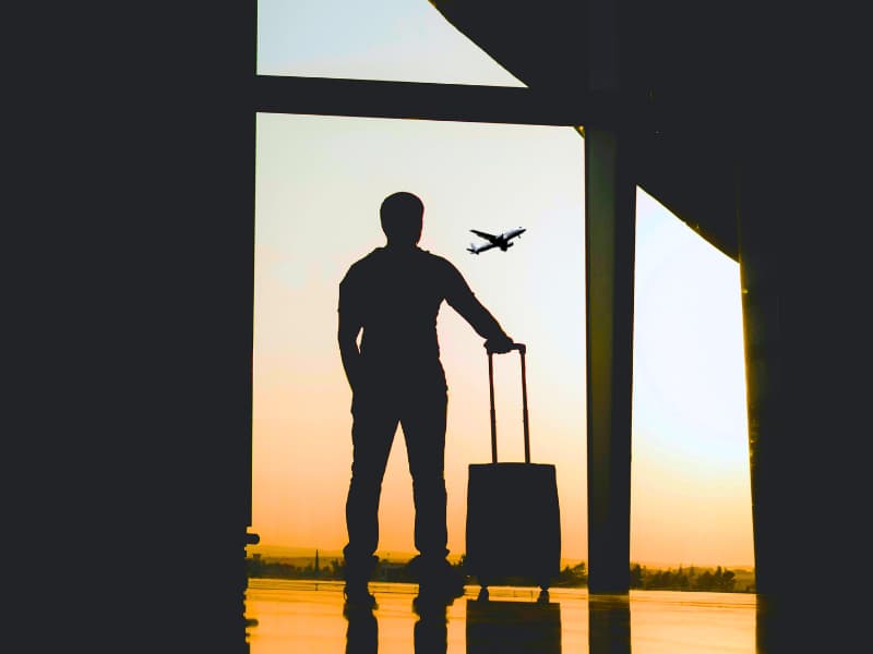 Silhouette of a solo traveler at the airport watching a plane take off—capturing the start of an international journey where having travel insurance for international travel can turn chaos into calm when plans fall apart abroad.