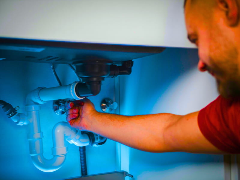 Licensed plumber upgrading outdated pipe systems, a home improvement often required to qualify for key Homeowners Insurance Discounts related to water damage prevention.