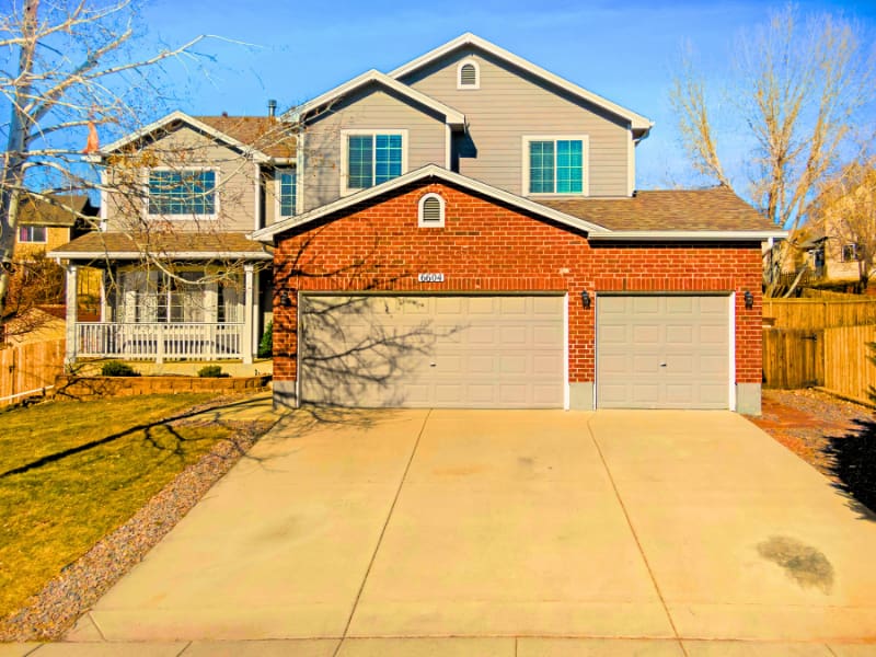 Mixed brick-and-siding two-story house with wide driveway and visible foundation — a style often reviewed when seeking the best home insurance for average family homes.