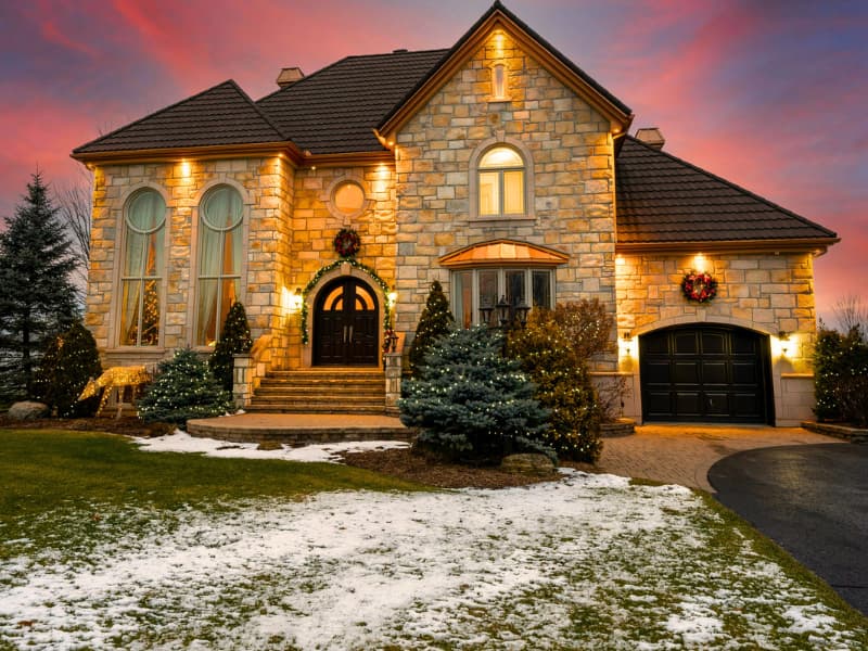 Elegant stone residence lit at dusk with landscaped entry — a high-value property type that often needs specialized coverage when finding the best home insurance.