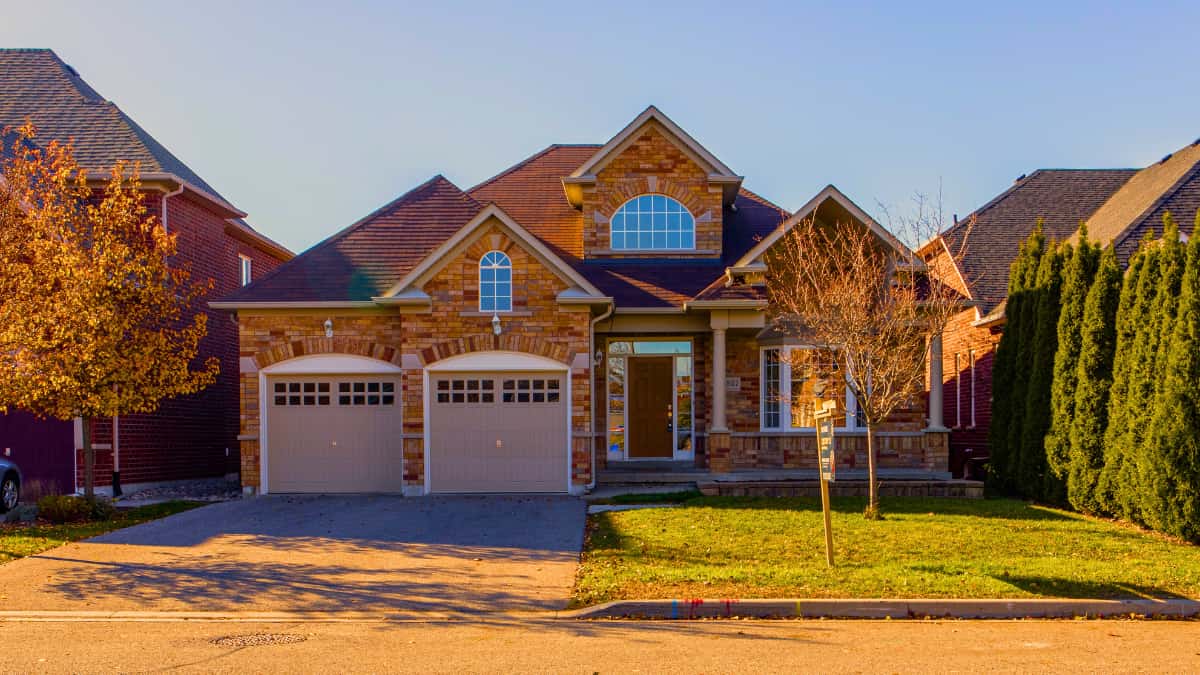 Front view of a brick single-family home with a two-car garage and tidy lawn — a common property style people review when comparing the best home insurance for suburban neighborhoods.
