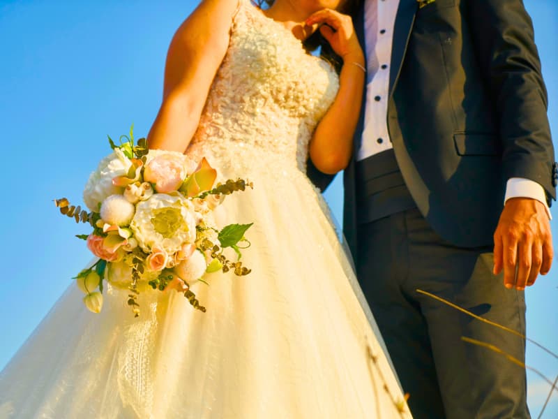 Bride holding a blush bouquet beside the groom at golden hour—simple, elegant reminder to compare wedding venue insurance options.